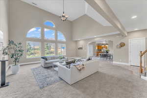 Carpeted living room featuring a high ceiling and an inviting chandelier