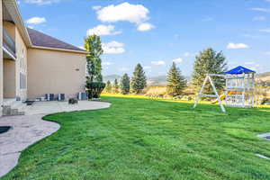 View of yard featuring a playground, central air condition unit, a patio area, and a mountain view