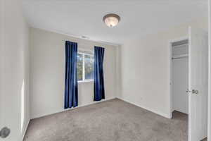 Unfurnished bedroom featuring a closet and light colored carpet