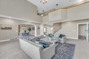 Carpeted living room with a towering ceiling and a chandelier