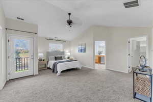 Carpeted bedroom with ceiling fan, connected bathroom, a walk in closet, access to exterior, and vaulted ceiling