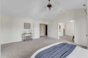 Carpeted bedroom featuring ceiling fan and vaulted ceiling