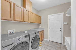 Laundry area with a textured ceiling, independent washer and dryer, and cabinets