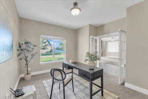 Carpeted office space featuring french doors