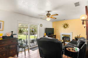 Living room with light wood-type flooring, ceiling fan, and a textured ceiling