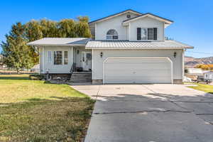 View of front of property with a garage, a mountain view, and a front lawn