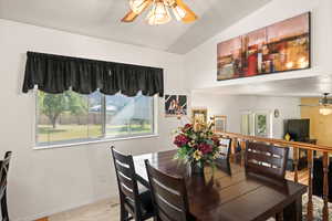 Carpeted dining space with ceiling fan and vaulted ceiling