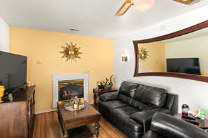 Living room with ceiling fan and dark wood-type flooring