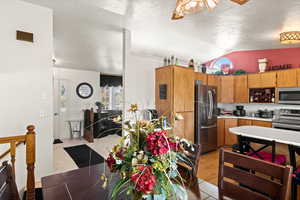 Kitchen featuring lofted ceiling, appliances with stainless steel finishes, light hardwood / wood-style flooring, and a textured ceiling