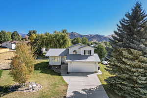 View of front of house with a front yard, a mountain view, and a garage