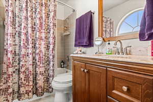 Full bathroom with shower / tub combo with curtain, vanity, and toilet