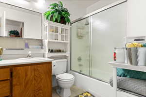 Full bathroom featuring tile patterned flooring, enclosed tub / shower combo, vanity, and toilet