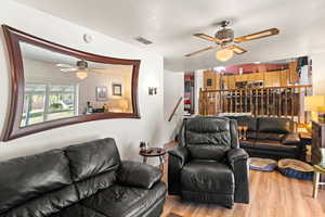 Living room featuring light wood-type flooring, ceiling fan, and a textured ceiling