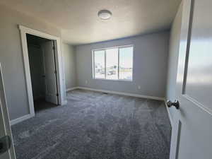 Unfurnished bedroom with a textured ceiling and dark colored carpet