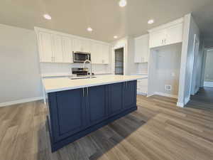 Kitchen featuring white cabinets, a kitchen island with sink, stainless steel appliances, and sink