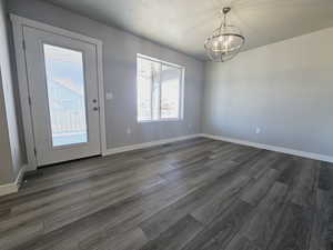 Unfurnished dining area with a notable chandelier and dark hardwood / wood-style floors