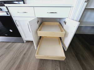 Interior details featuring stainless steel stove, hardwood / wood-style flooring, and white cabinetry