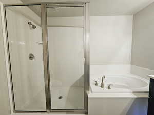 Bathroom with a textured ceiling, vanity, and shower with separate bathtub