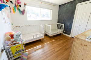 Bedroom with wood-type flooring and a nursery area