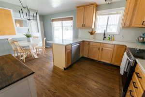 Kitchen with dark hardwood / wood-style flooring, sink, kitchen peninsula, backsplash, and appliances with stainless steel finishes