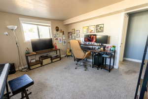 Carpeted home office featuring a textured ceiling