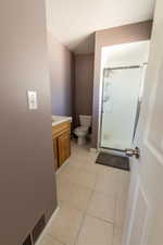 Bathroom with tile patterned flooring, vanity, walk in shower, and toilet