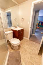 Bathroom with toilet, tile patterned flooring, vanity, and a shower with shower door