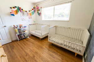 Bedroom featuring a nursery area and hardwood / wood-style floors