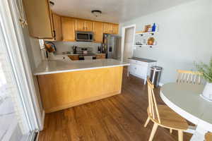 Kitchen featuring kitchen peninsula, dark hardwood / wood-style floors, and appliances with stainless steel finishes