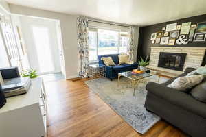 Living room with a stone fireplace and hardwood / wood-style flooring