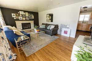 Living room with wood-type flooring and a stone fireplace