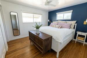 Bedroom featuring dark hardwood / wood-style flooring, multiple windows, and ceiling fan