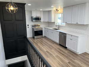 Kitchen with appliances with stainless steel finishes, pendant lighting, and white cabinetry