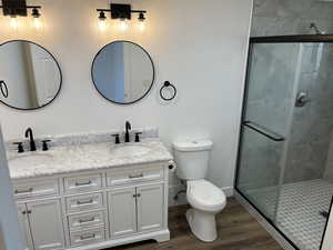 Bathroom featuring walk in shower, hardwood / wood-style floors, vanity, and toilet