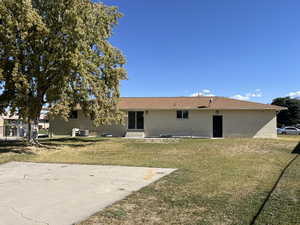 Back of property with central AC and a lawn