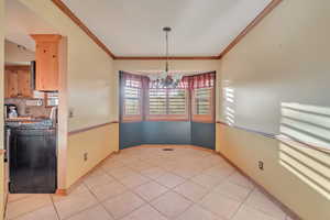 Tiled dining space featuring a notable chandelier and crown molding