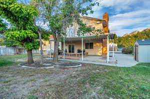 Rear view of property with a storage shed, a patio area, and a yard