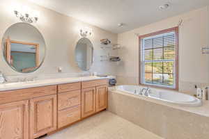 Bathroom with vanity, tile patterned floors, and a relaxing tiled tub