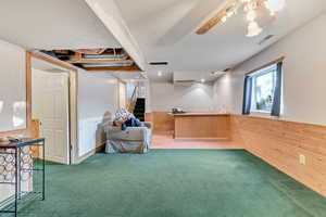 Basement with wooden walls, ceiling fan, carpet floors, and sink