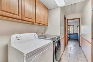 Washroom featuring cabinets, independent washer and dryer, and light tile patterned floors