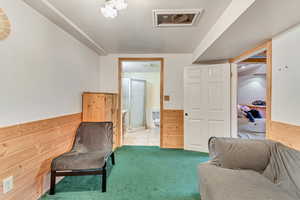 Living area featuring wooden walls and light carpet