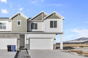 Townhome / multi-family property featuring stone siding, board and batten siding, concrete driveway, and a mountain view