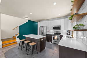 Kitchen featuring a kitchen island, dark hardwood / wood-style flooring, a breakfast bar, sink, and appliances with stainless steel finishes