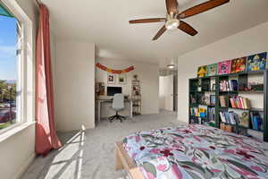 Bedroom with ceiling fan, light colored carpet, and multiple windows