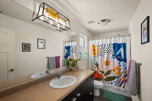 Bathroom featuring a shower with curtain, vanity, and toilet