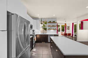 Kitchen with white cabinets, a kitchen island, dark brown cabinets, plenty of natural light, and stainless steel appliances