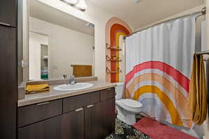 Bathroom featuring curtained shower, vanity, and toilet