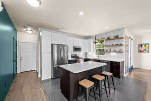 Kitchen featuring sink, a kitchen island, stainless steel appliances, dark hardwood / wood-style floors, and a kitchen breakfast bar