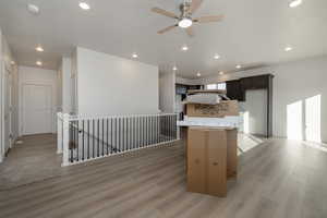 Kitchen with ceiling fan, a kitchen island, and light wood-type flooring