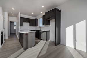 Kitchen with dishwasher, a center island, sink, and light hardwood / wood-style floors